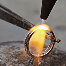 Gold ring being worked on with a torch