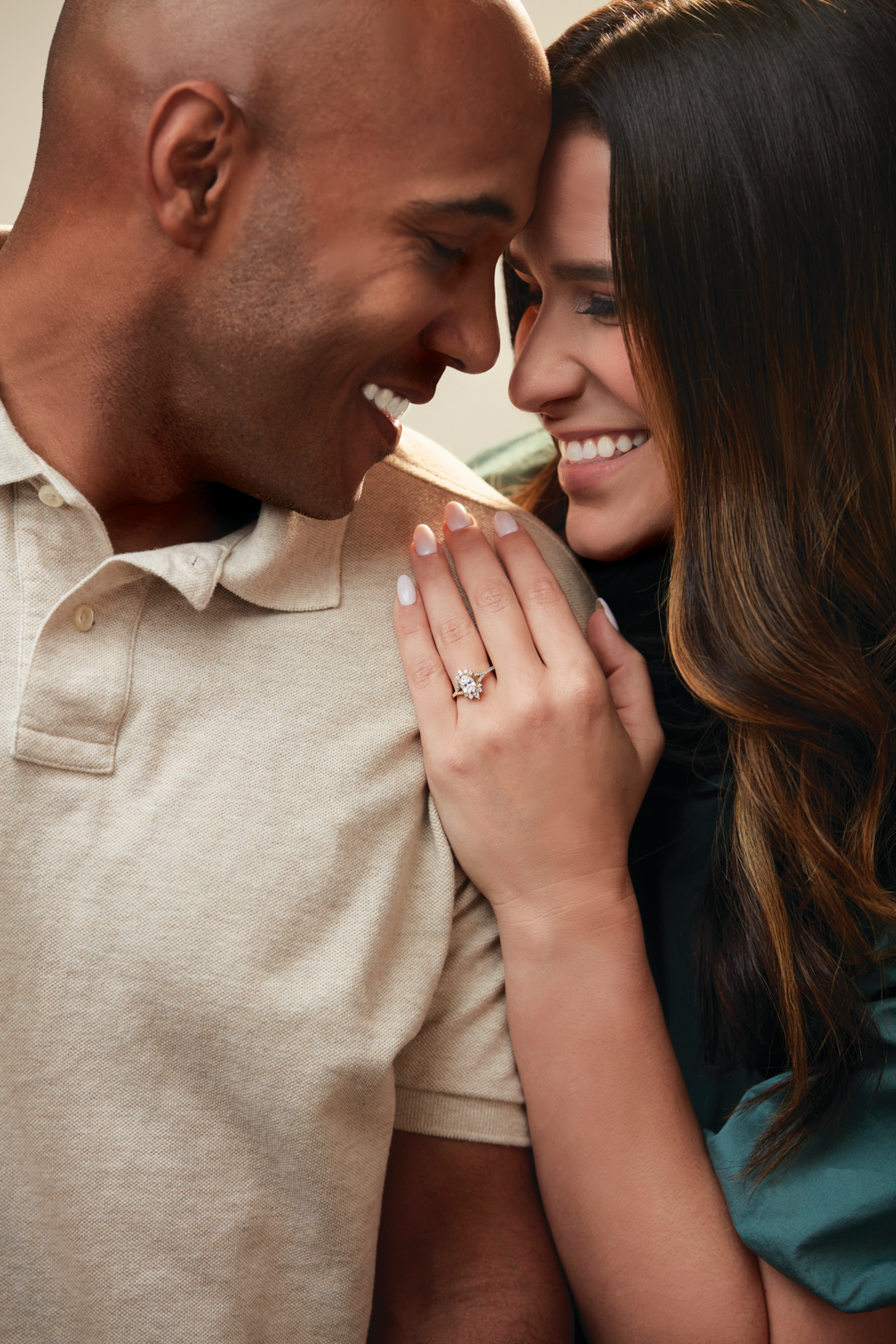 Man and woman smiling at each other with a close-up of the woman's hand wearing a ring.