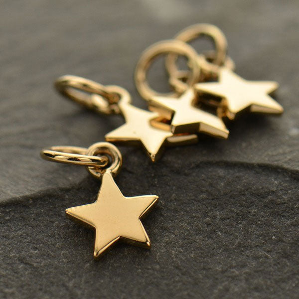 Four golden-coloured bronze five-point star charms with attached jump rings.