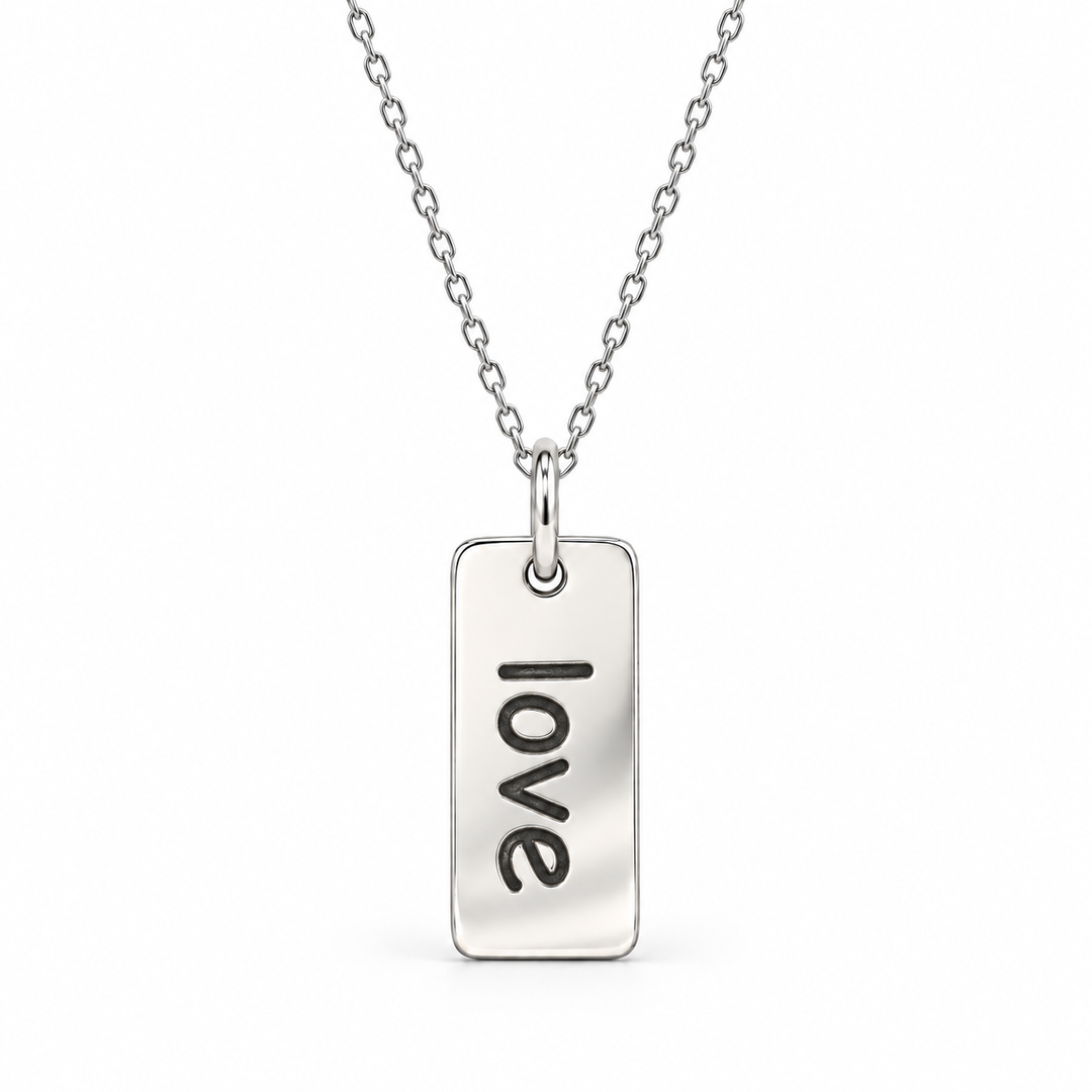 Sterling silver necklace with a rectangular tag pendant engraved with “love” in lowercase letters, suspended from a fine cable chain.