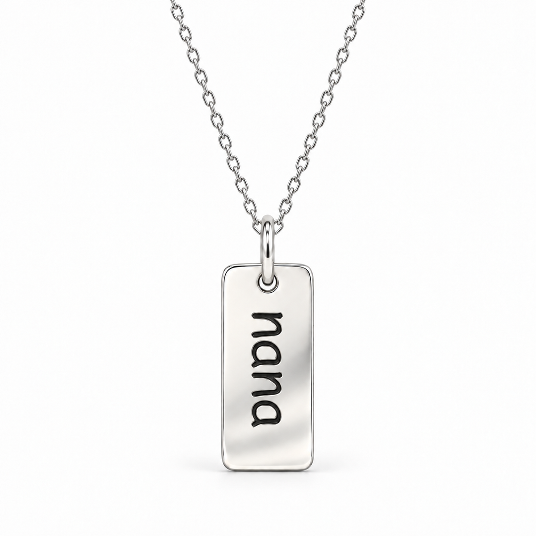 Sterling silver necklace with a rectangular tag pendant engraved with “nana” in lowercase letters, suspended from a fine cable chain.