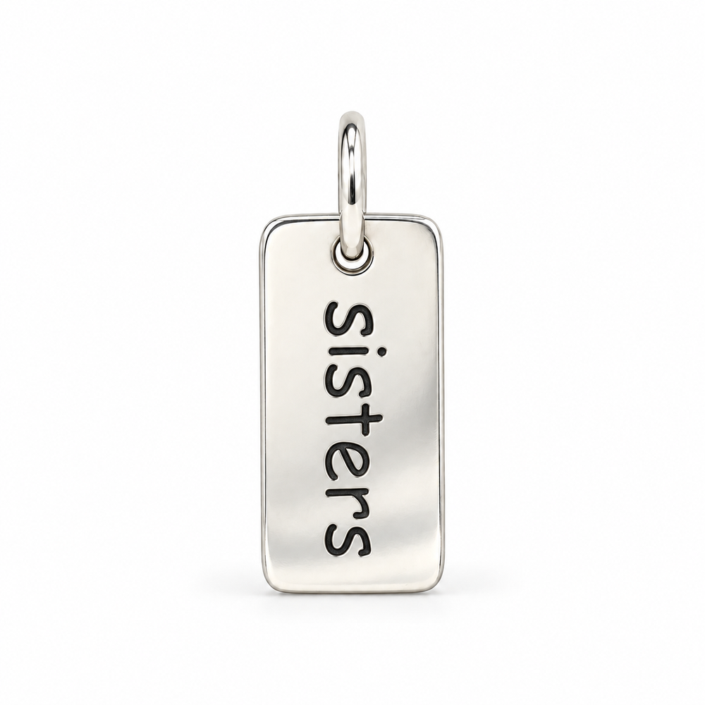 Rectangular sterling silver tag charm with rounded corners, engraved with “sisters” in lowercase letters, with a silver jump ring.
