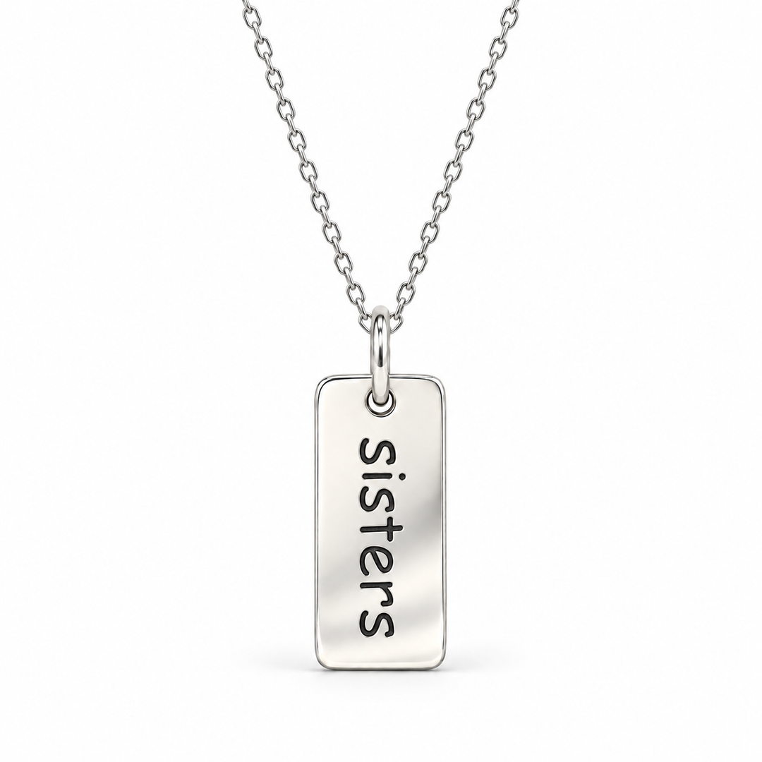 Sterling silver necklace with a rectangular tag pendant engraved with “sisters” in lowercase letters, suspended from a fine cable chain.